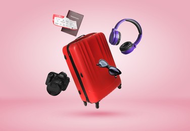 Image of Suitcase, passport, ticket, headphones, sunglasses and camera in air on pink background. Ready to travel