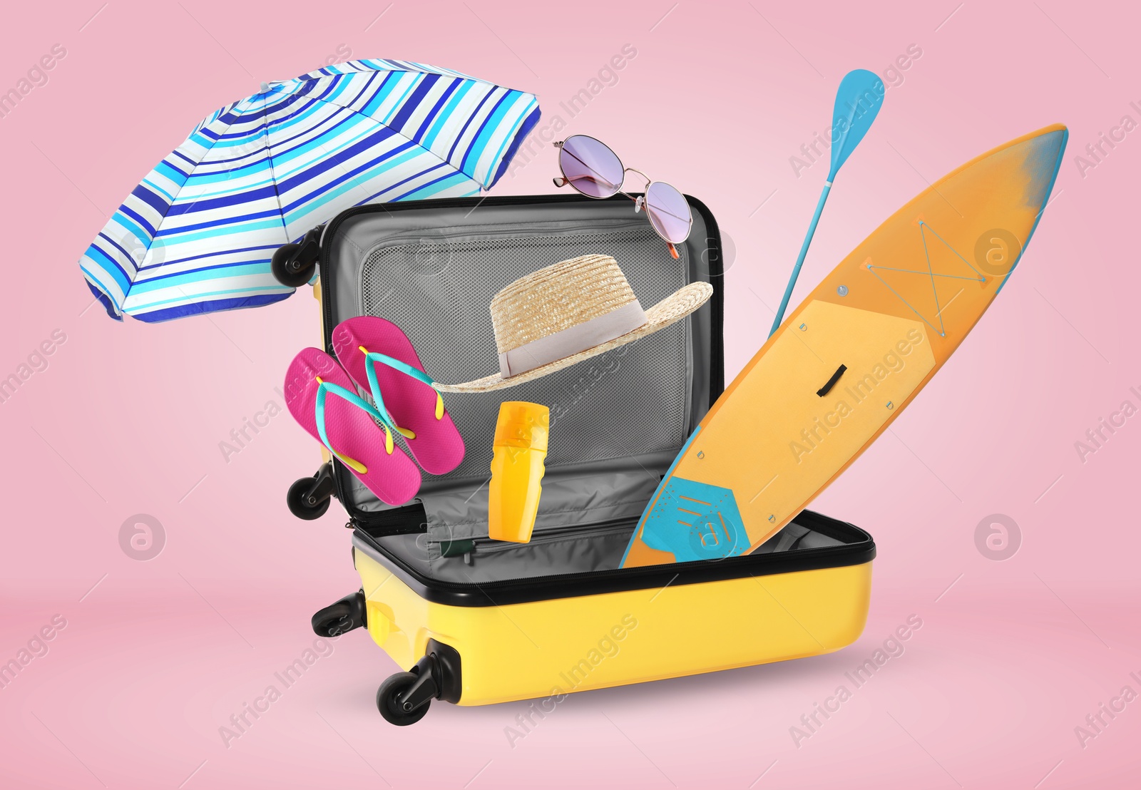 Image of Suitcase and flying beach items on pink background. Ready to travel