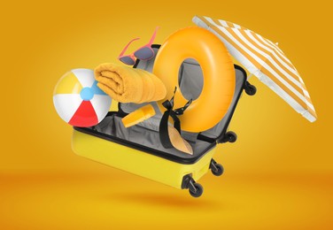 Image of Suitcase and beach items in air on orange background. Ready to travel