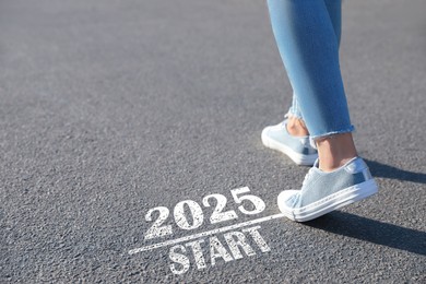 Image of Woman walking near sign 2025 Start on asphalt, closeup. Concept of new year, fresh beginning