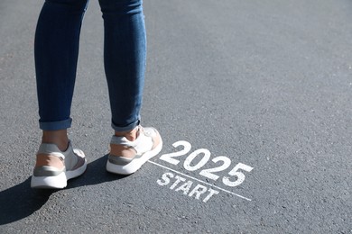 Woman walking near sign 2025 Start on asphalt, closeup. Concept of new year, fresh beginning