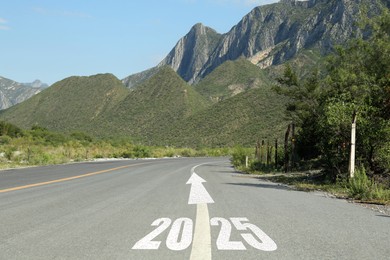 Image of 2025 and arrow on asphalt road in mountains. Concept of new year, fresh beginning