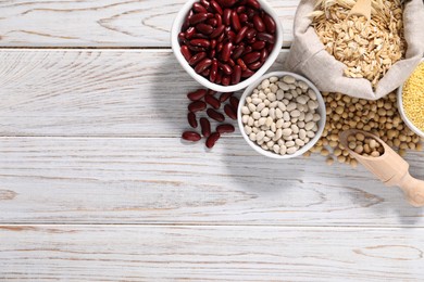 Photo of Different types of legumes and cereals on white wooden table, flat lay. Space for text