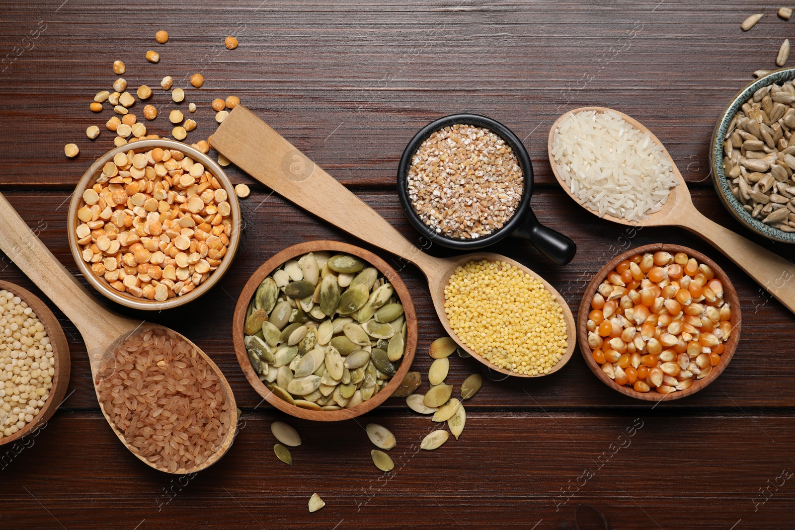 Photo of Different types of seeds and cereals on wooden table, flat lay