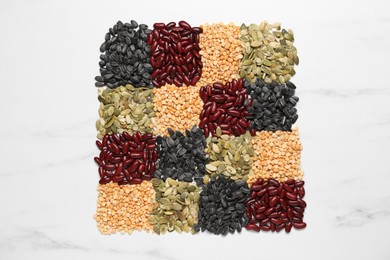 Photo of Different types of legumes and seeds on white marble table, top view