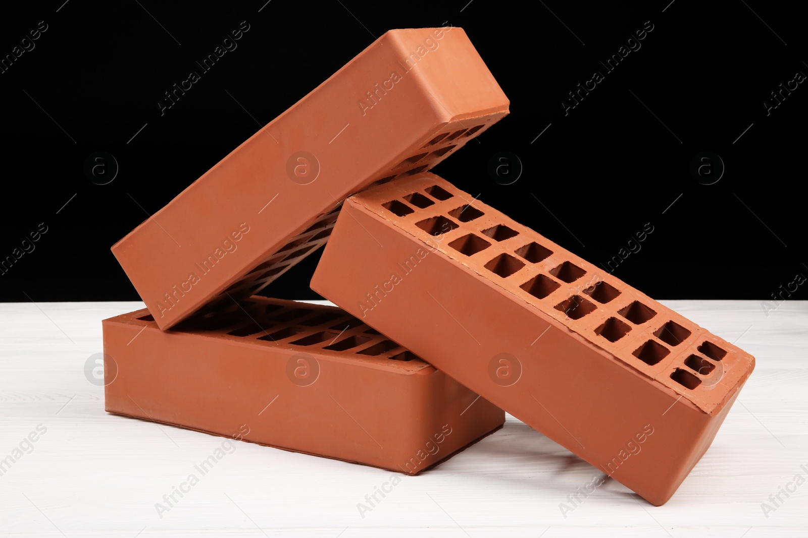 Photo of Red bricks on white wooden table. Building material