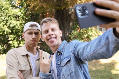 Happy brothers taking selfie and gesturing outdoors