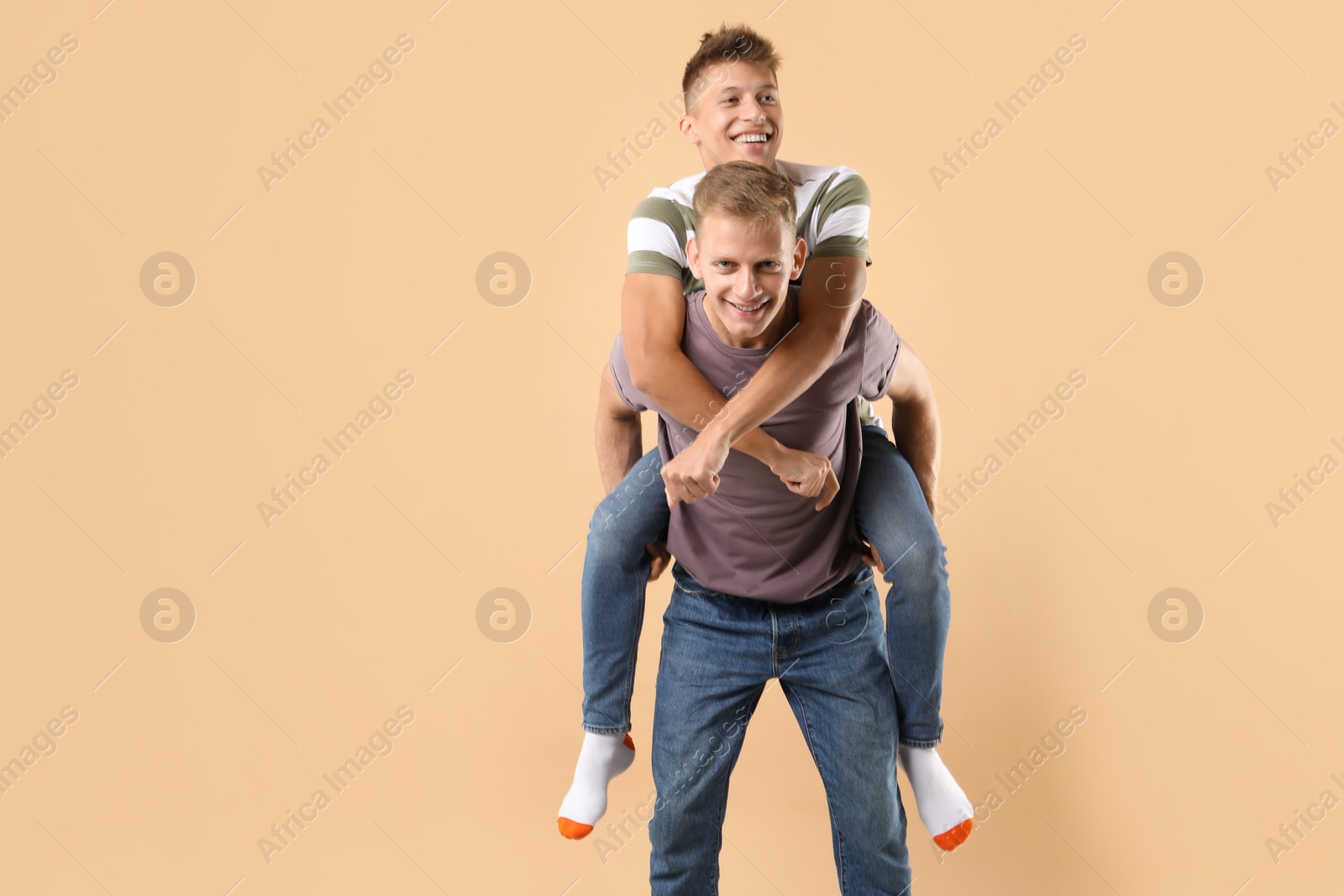 Photo of Happy brothers on beige background. Space for text