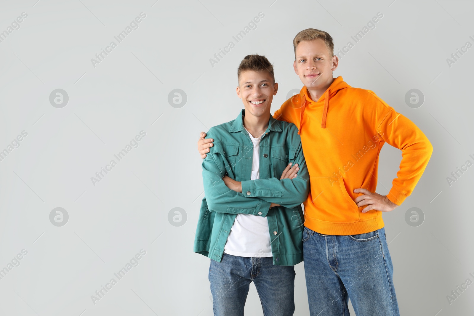 Photo of Two happy brothers posing on light background. Space for text