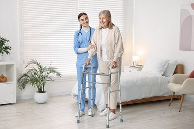 Photo of Nurse helping senior woman with walking frame in clinic