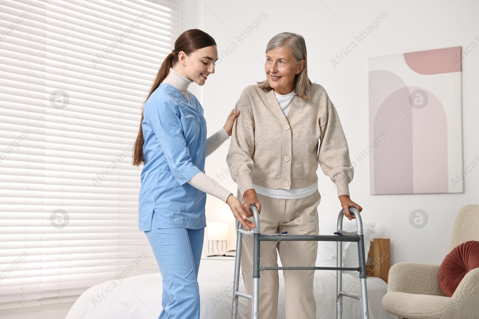 Photo of Nurse helping senior woman with walking frame in clinic