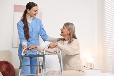 Nurse helping senior woman with walking frame in clinic