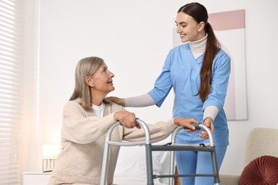 Nurse helping senior woman with walking frame in clinic