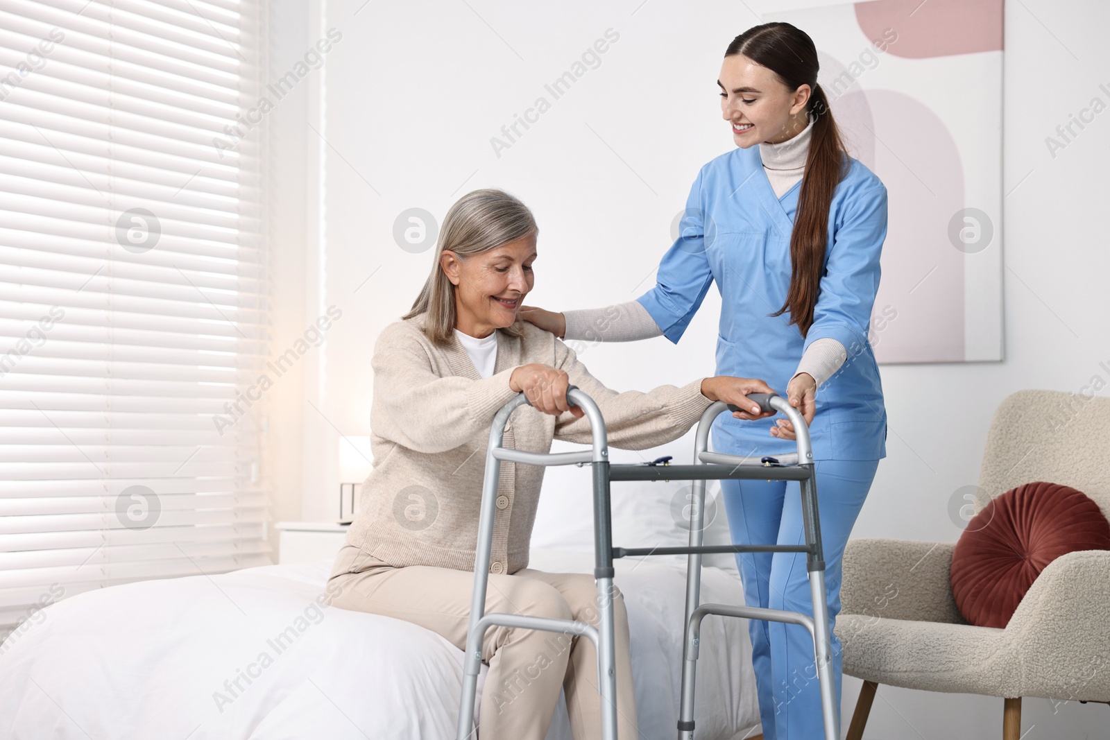 Photo of Nurse helping senior woman with walking frame in clinic