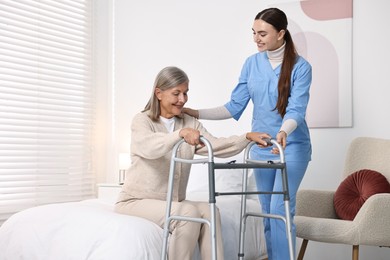 Nurse helping senior woman with walking frame in clinic