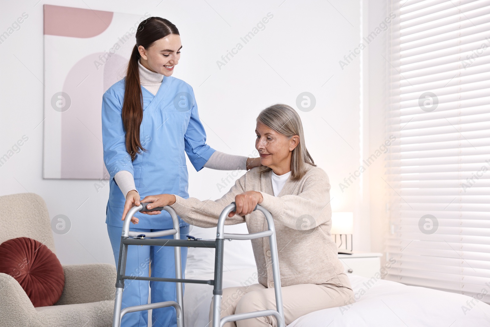 Photo of Nurse helping senior woman with walking frame in clinic