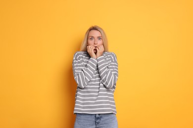 Portrait of scared woman on orange background