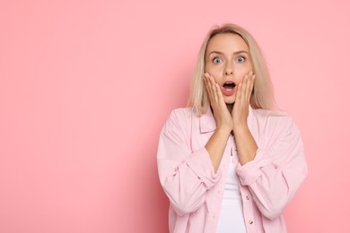 Portrait of scared woman on pink background, space for text