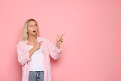 Portrait of scared woman on pink background, space for text