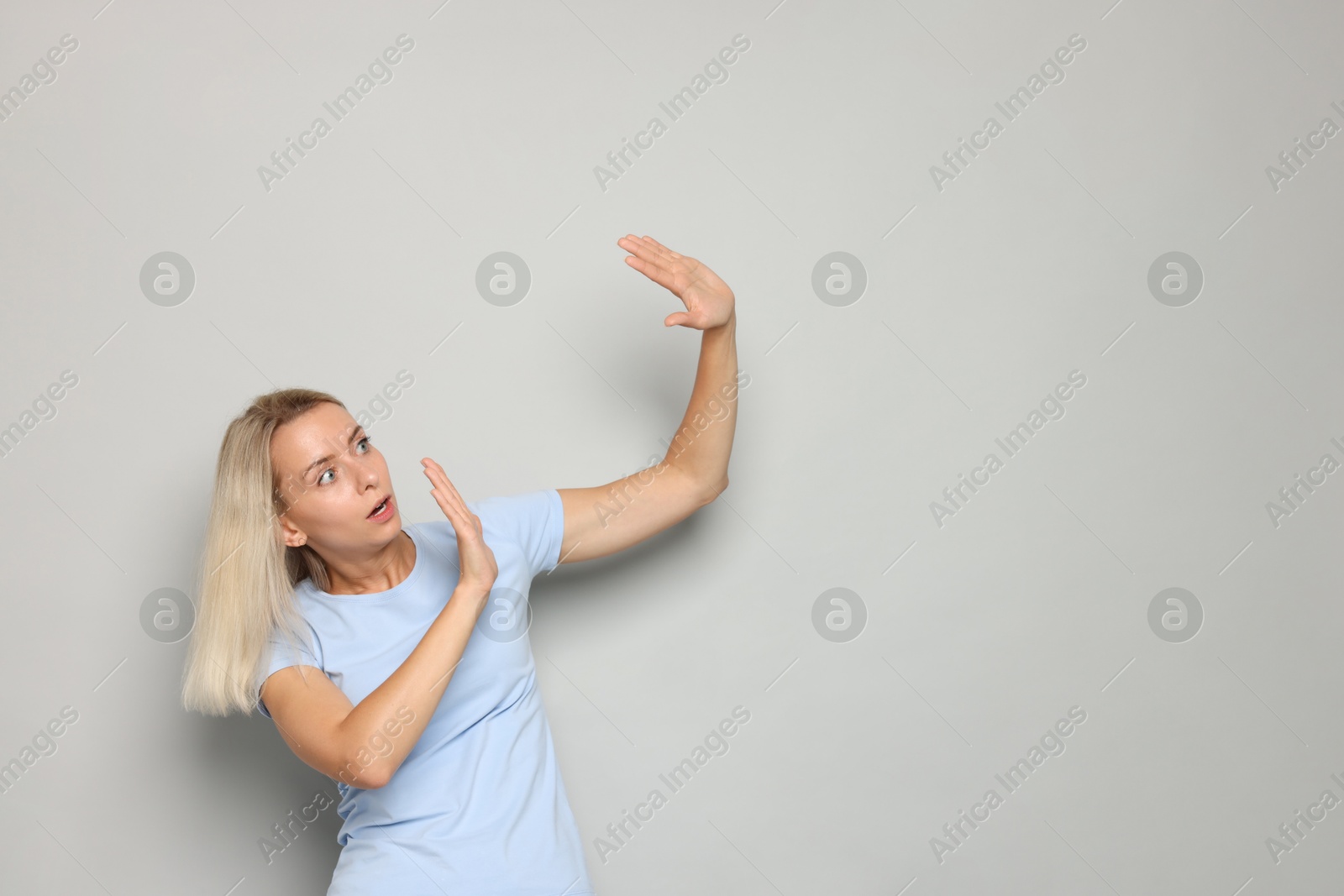 Photo of Portrait of scared woman on gray background, space for text