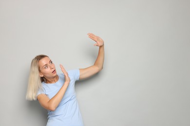 Photo of Portrait of scared woman on gray background, space for text