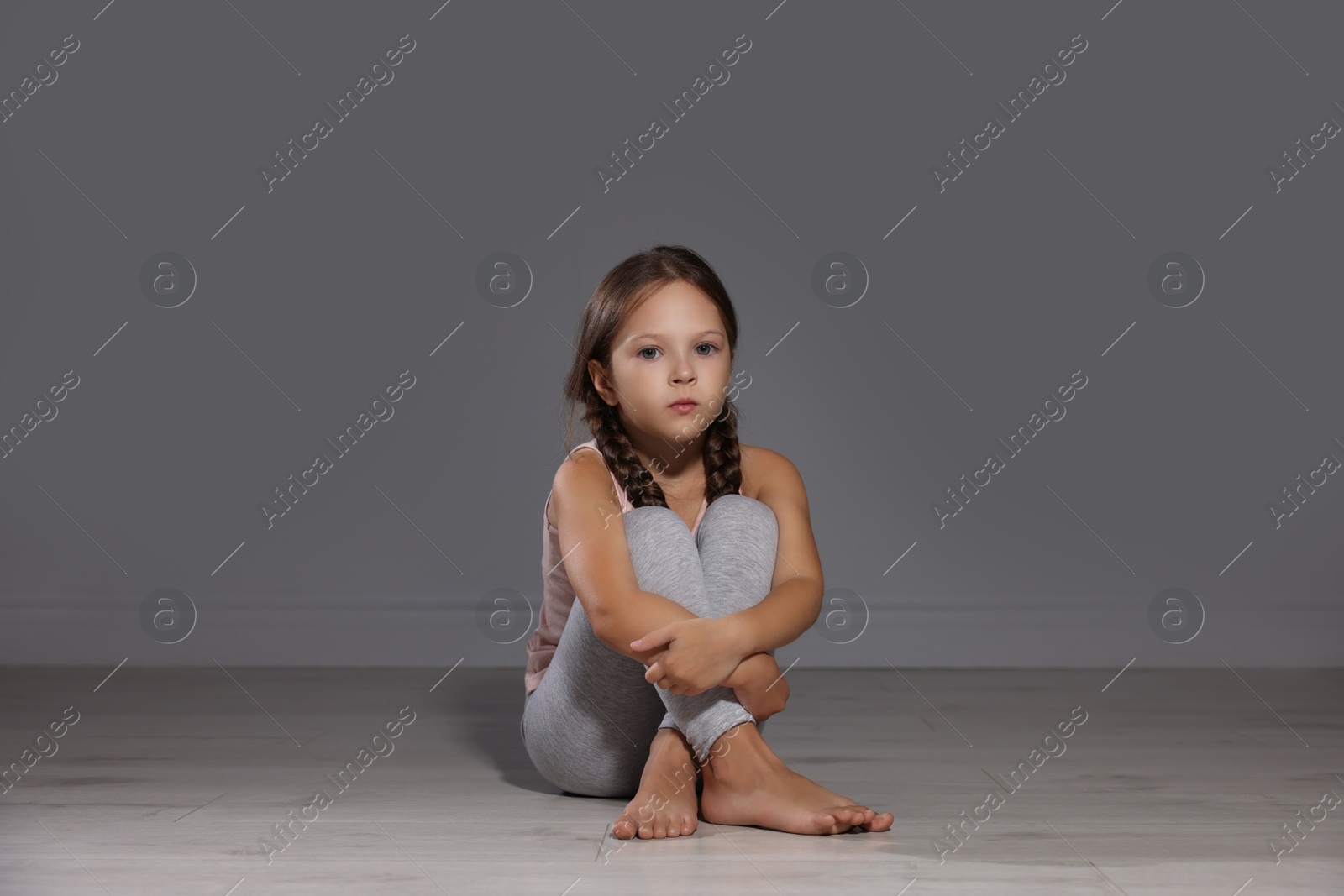 Photo of Orphanage concept. Sad girl sitting on floor indoors