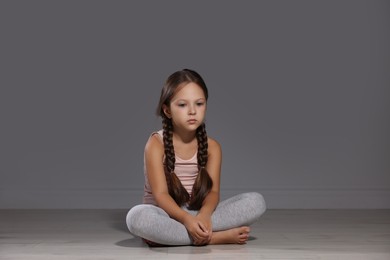 Orphanage concept. Sad girl sitting on floor indoors