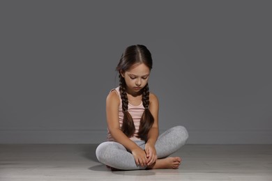 Photo of Orphanage concept. Sad girl sitting on floor indoors