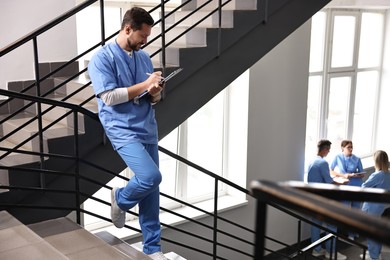 Healthcare workers in hospital, selective focus. Nurse with clipboard writing notes indoors