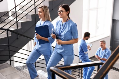 Healthcare workers with tablet and clipboard walking up stairs in hospital