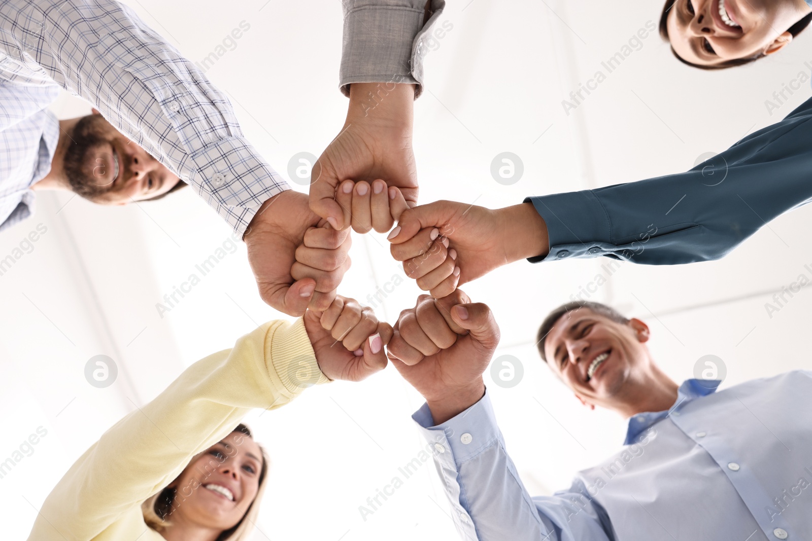 Photo of Teamwork. Group of employees joining hands in office, bottom view