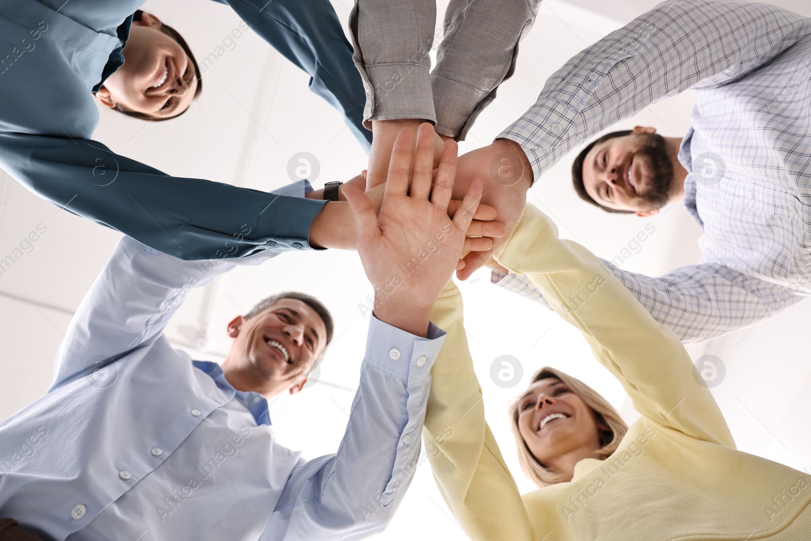 Photo of Teamwork. Group of employees joining hands in office, bottom view