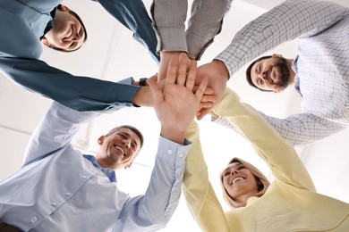 Teamwork. Group of employees joining hands in office, bottom view