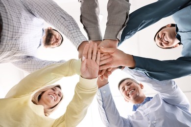 Photo of Teamwork. Group of employees joining hands in office, bottom view