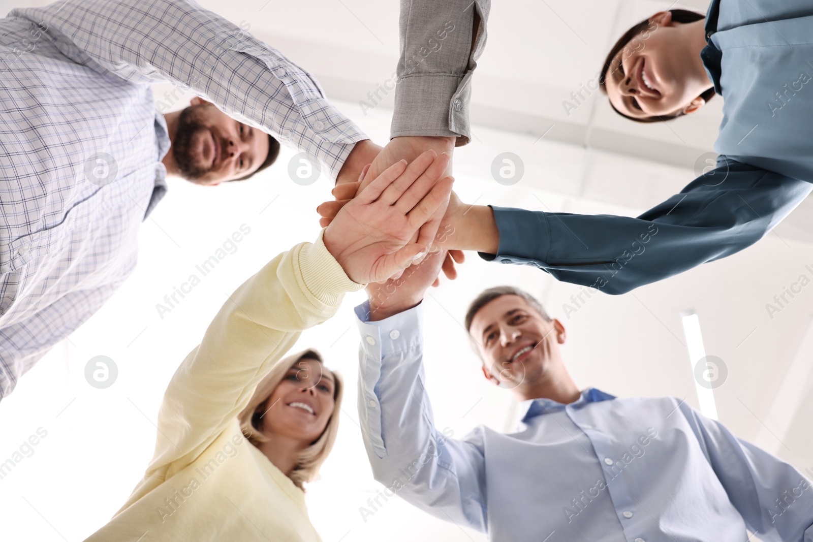 Photo of Teamwork. Group of employees joining hands in office, bottom view