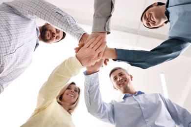 Photo of Teamwork. Group of employees joining hands in office, bottom view