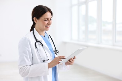 Photo of Smiling healthcare worker using tablet in hospital