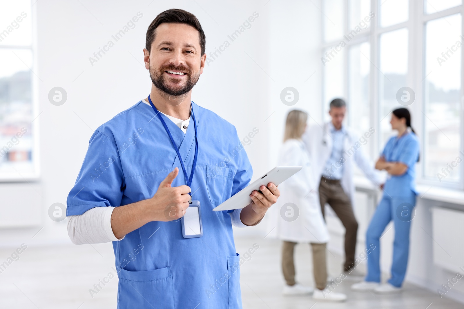 Photo of Healthcare workers in hospital, selective focus. Nurse with tablet showing thumbs up indoors