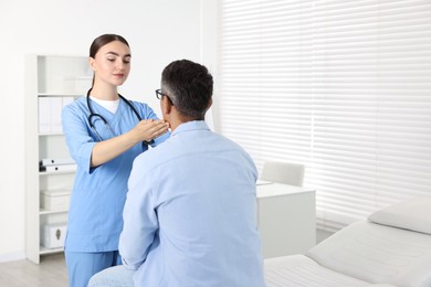 Photo of Doctor examining man's throat in clinic during appointment