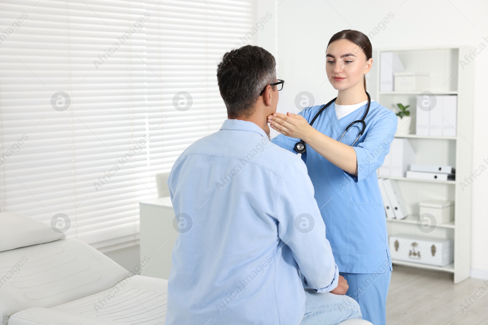 Photo of Doctor examining man's throat in clinic during appointment