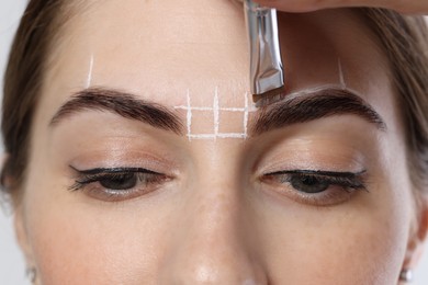 Photo of Young woman undergoing henna eyebrows dyeing procedure, closeup