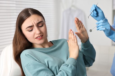 Photo of Dental phobia. Dentist working with scared woman in clinic, closeup