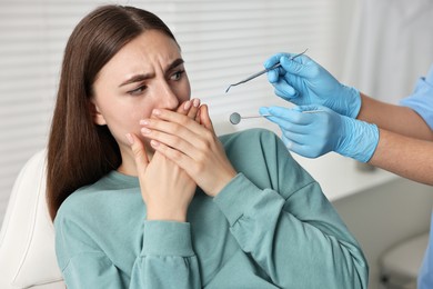 Dental phobia. Dentist working with scared woman in clinic, closeup