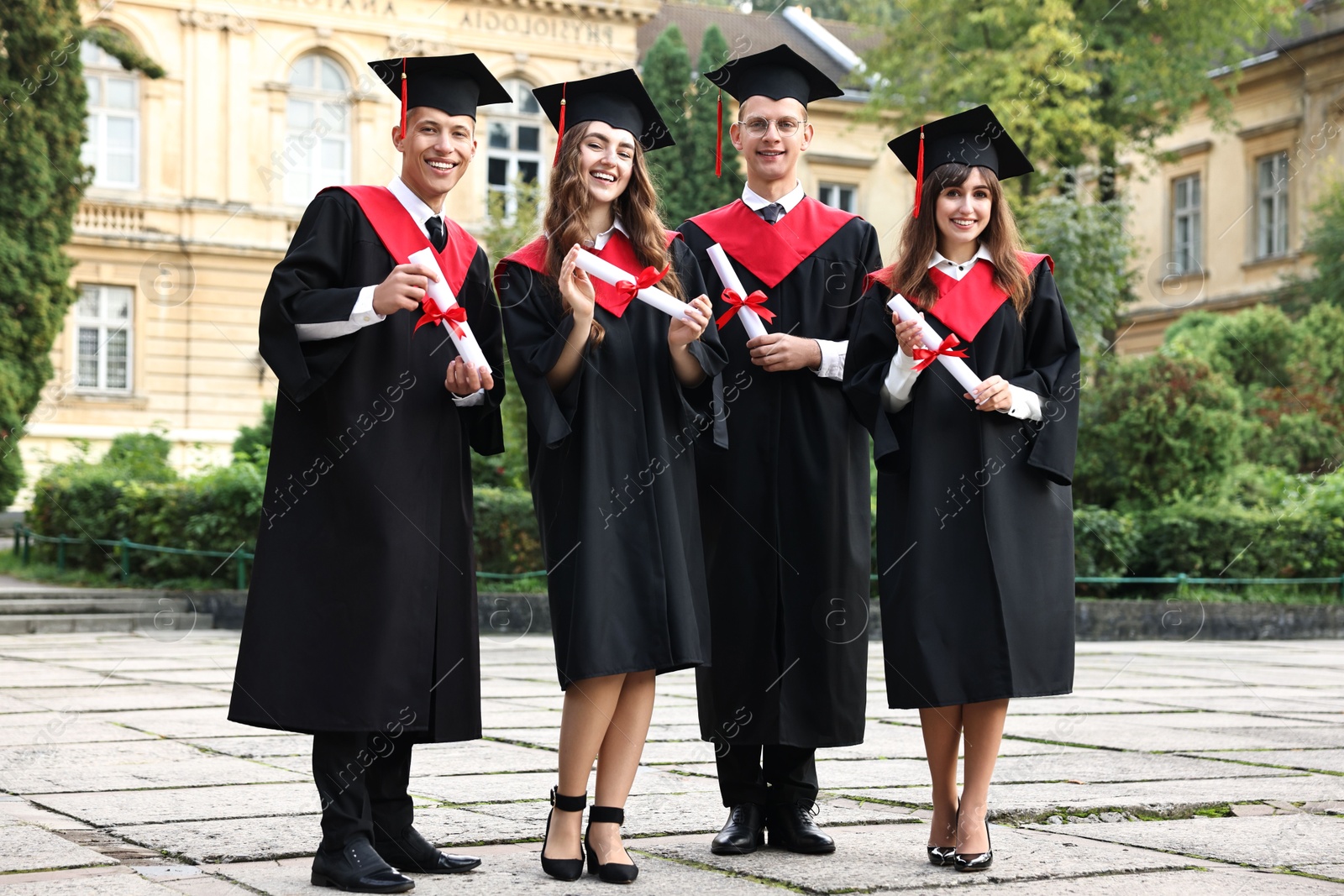 Photo of Happy students with diplomas after graduation ceremony outdoors