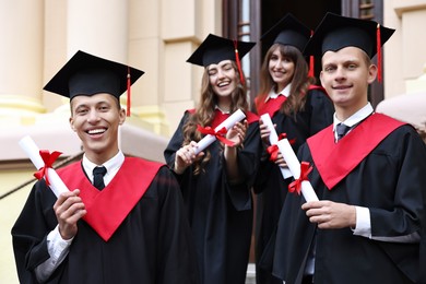 Graduation ceremony. Happy students with diplomas outdoors, selective focus