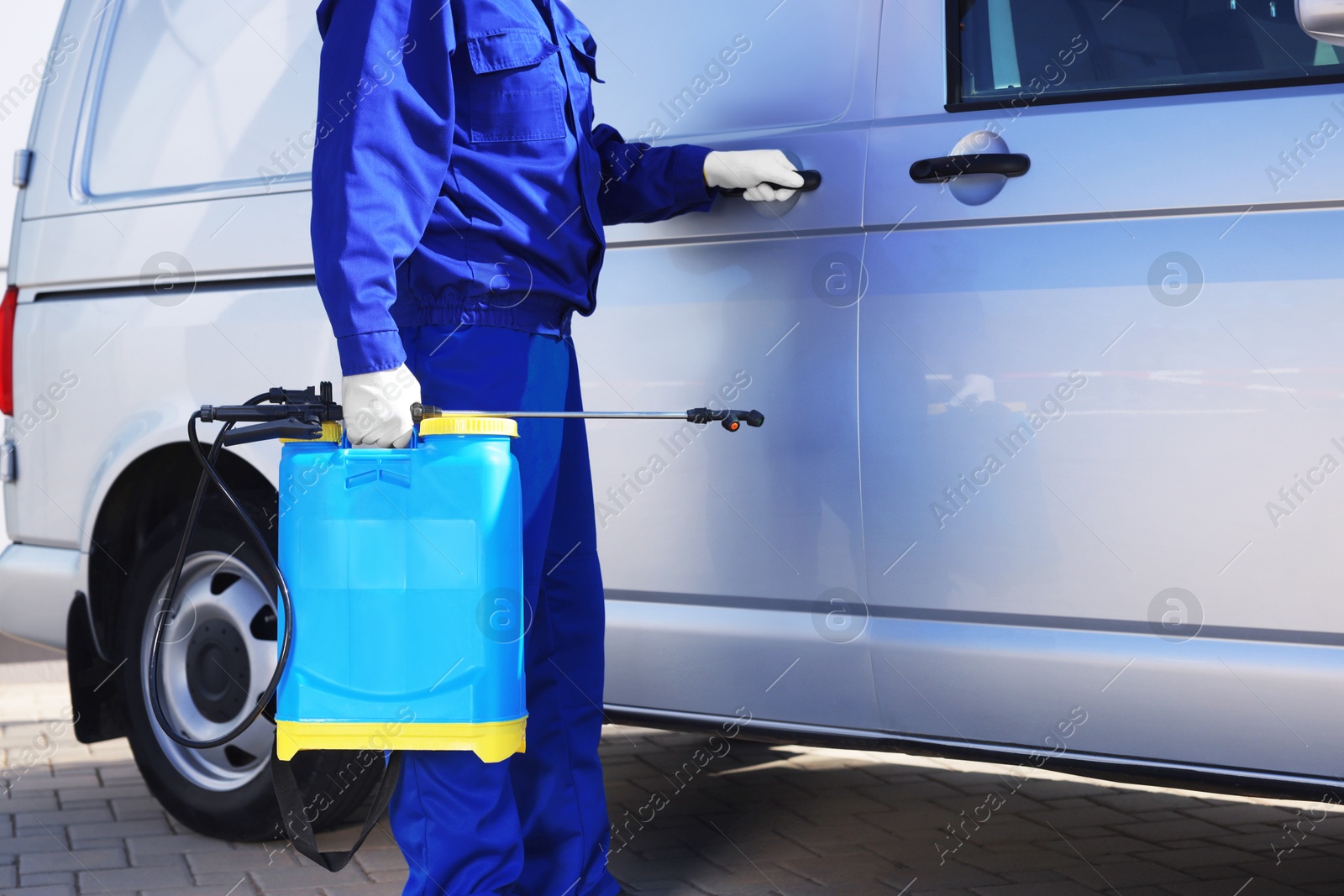 Photo of Pest control worker with spray tank near gray minibus outdoors, closeup