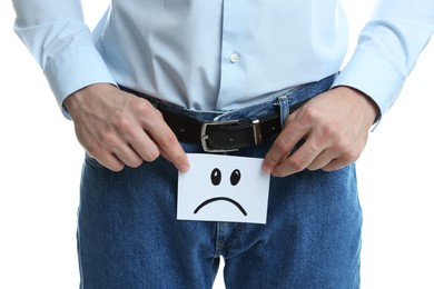 Photo of STD (sexually transmitted diseases). Man holding sticky note with drawn sad face on white background, closeup