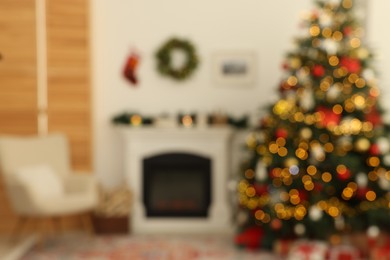 Blurred view of decorated Christmas tree near fireplace in room. Festive interior design