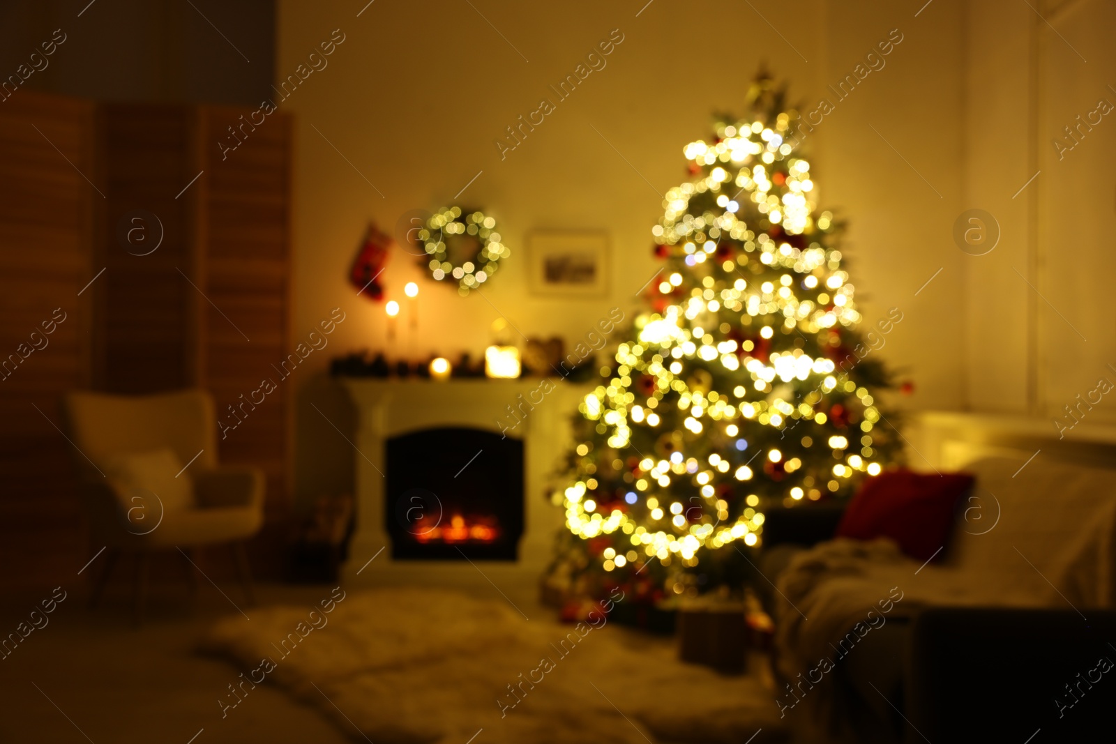 Photo of Blurred view of decorated Christmas tree near fireplace in room. Festive interior design