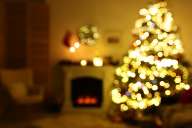 Blurred view of decorated Christmas tree near fireplace in room. Festive interior design